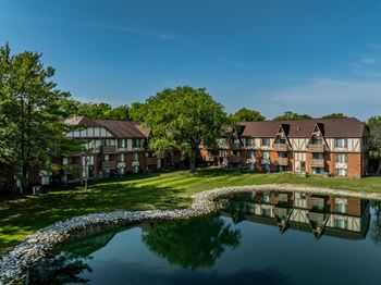 An apartment complex with a pond in front of it